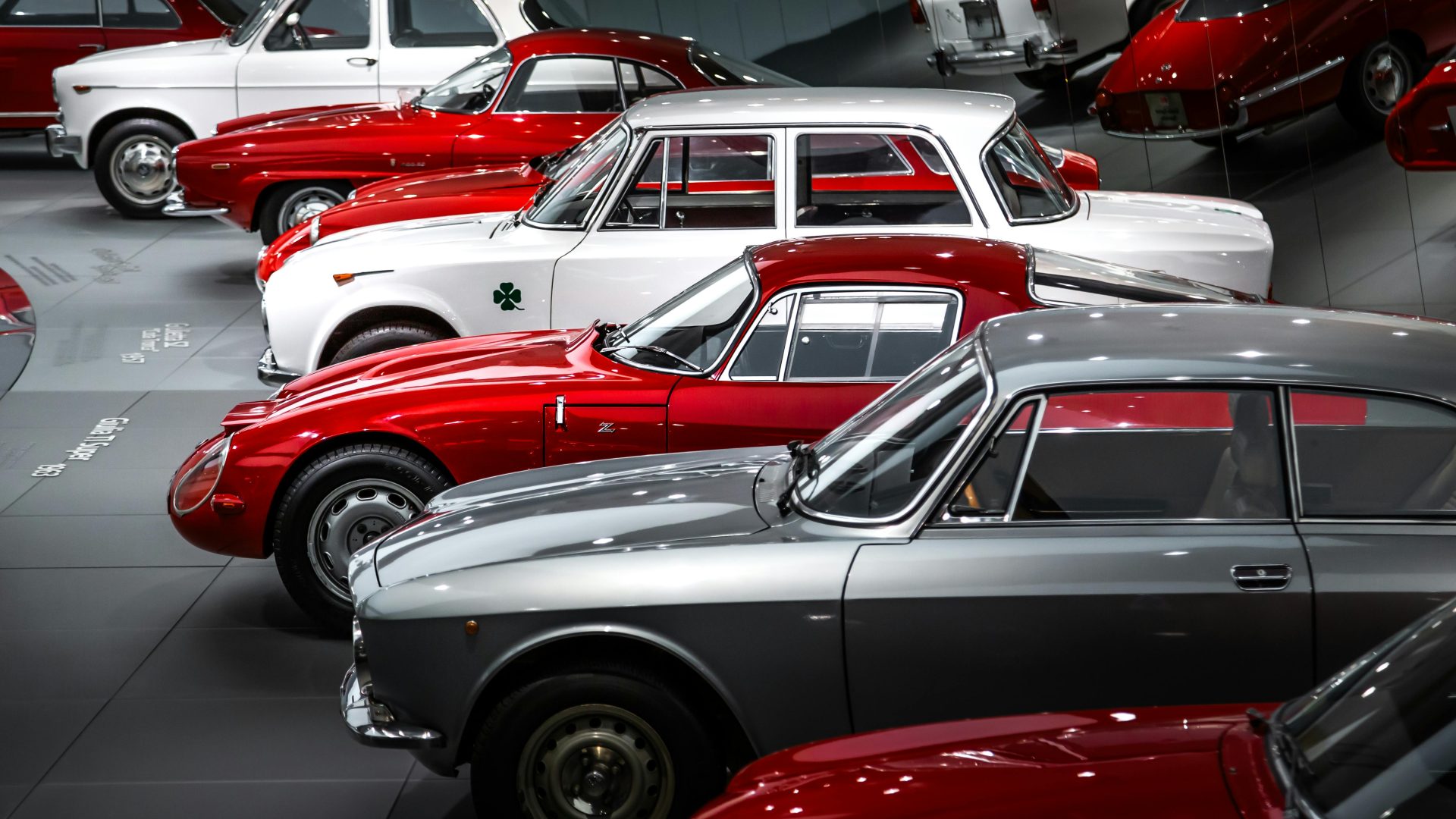 Eine beeindruckende Sammlung klassischer Alfa Romeo-Fahrzeuge, wunderschön präsentiert in einem Museumsumfeld.
